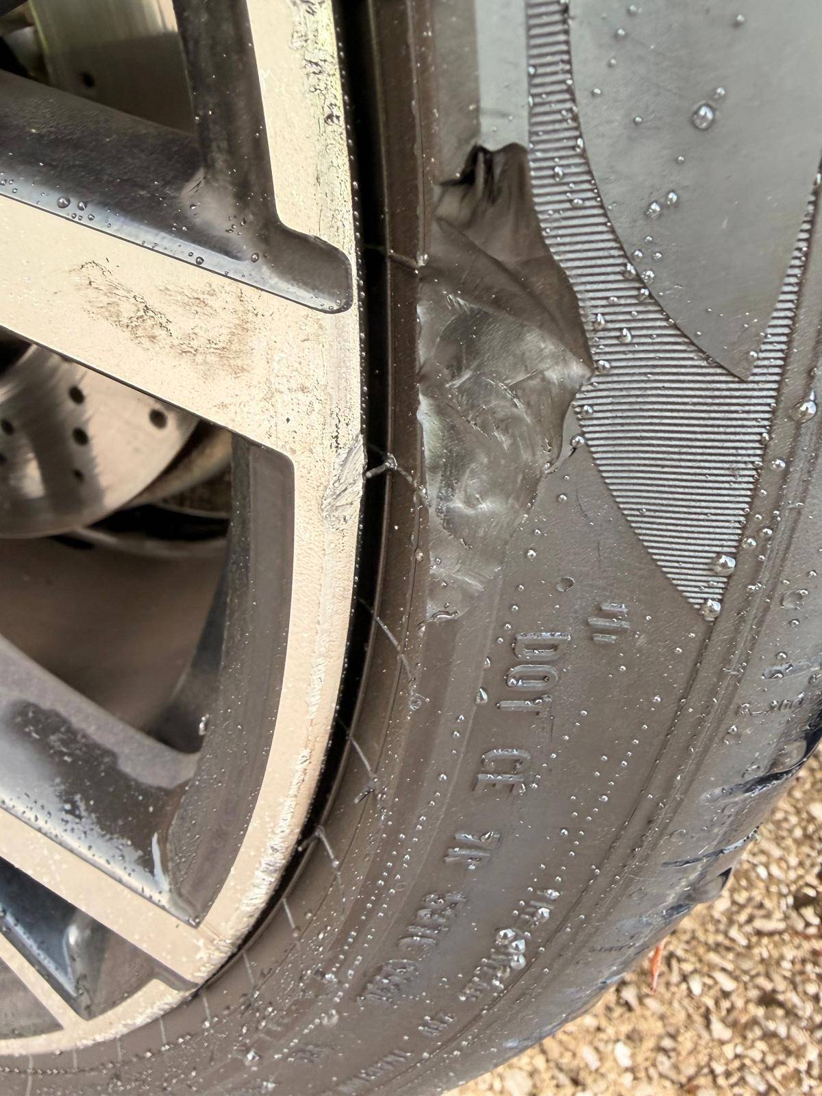 Torn tyre sidewall beside an alloy wheel