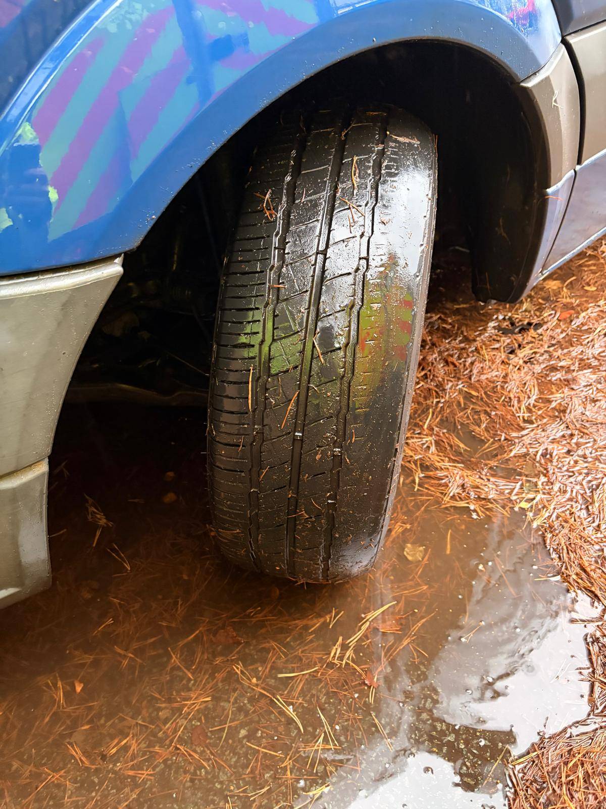 Front tyre inspected on a blue van