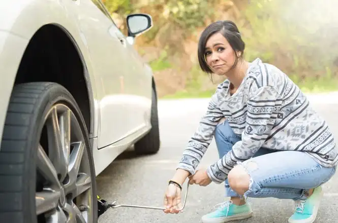 Young Women Changing A Flat Tire